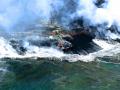 CLOSE UP OF VOLCANIC ISLAND CREATION PROCESS ON THE BIG ISLAND OF HAWAII-NOTE THE WAVE EROSION ,TO THE RIGHT OF MAGMA, CREATING BLACK SAND BEACH